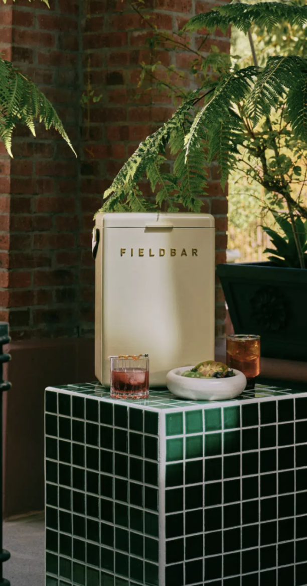 A cream Fieldbar cooler on a green tiled bar in a leafy courtyard
