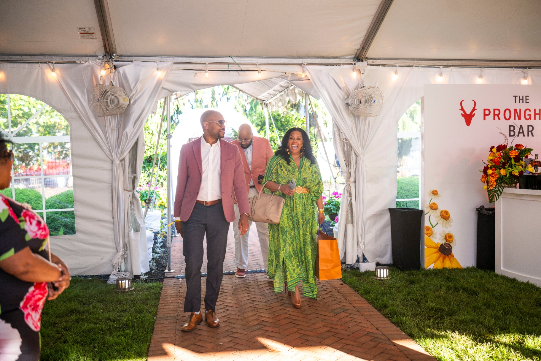 Guests arriving in tailored garden attire under a tented entrance