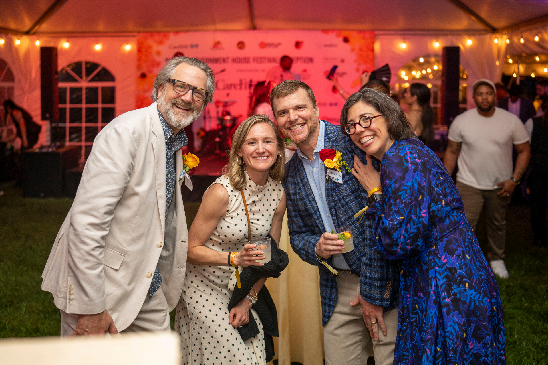 Four guests gathered together with cocktails inside the Governor's House tent